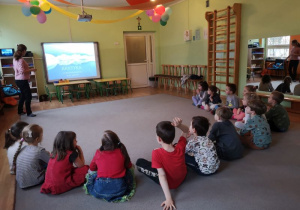 Dzieci oglądają prezentację wyświetlona na tablicy interaktywnej