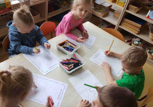 Dzieci wykonują ćwiczenia grafomotoryczne w kartach pracy