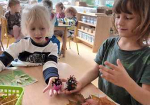 Ala i Rysiu prezentują swoje kompozycje - ślimaki z plasteliny oraz szyszek
