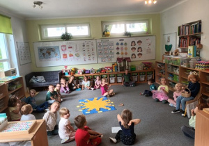 Zdjęcie przestawia grupę dzieci siedzących w kręgu podczas urodzin Tadzia, w środku kręgu leży pomoc edukacyjna "Urodzinowe Słoneczko"