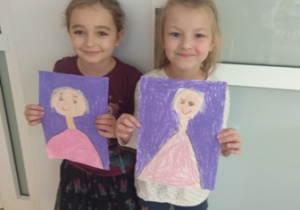 Dwie dziewczynki prezentują wykonane przez siebie portrety Marii Montessori