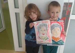 Dwóch chłopców prezentuje wykonane przez siebie portrety Marii Montessori