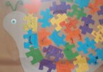 Zdjęcie prezentuje ślimaka wykonanego przez dzieci, którego skorupę tworzą kolorowe puzzle