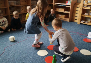 Chłopiec z dziewczynką ustawiają pionek na odpowiednim polu gry