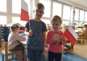 Chłopiec i dziewczynka pozują z wykonanymi przez siebie flagami