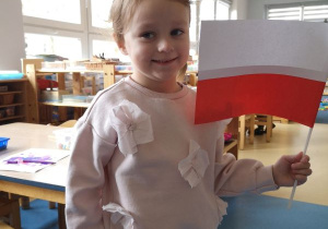 Dziewczynka pozuje z wykonaną przez siebie flagą