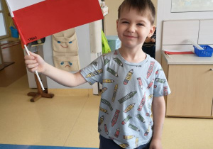 Chłopiec pozuje z wykonaną przez siebie flagą
