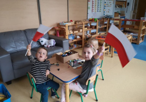 Chłopiec i dziewczynka pozują z wykonanymi przez siebie flagami