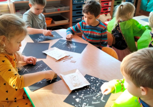 dzieci malują na czarnych kartonach techniką "Twal" używając białej farby