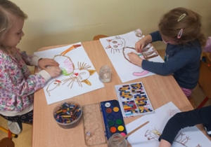 Dzieci w trakcie rysowania kota na dużych arkuszach papieru