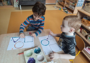 Rysio i Wojtuś w czasie stemplowania figur geometrycznych