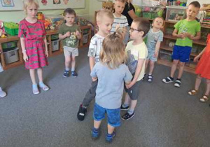 Dzieci tańczą na dywanie podczas zabawy ruchowej do piosenki pt. "Spotkanie na polanie"