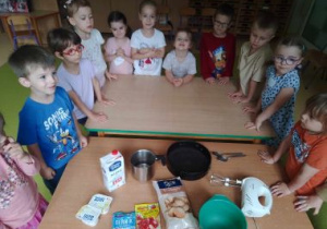 Dzieci stoją przy stolikach w oczekiwaniu na rozpoczęcie robienia ciasta