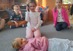 dziewczynka odgrywa scenkę, w trakcie której dzwoni na pogotowie