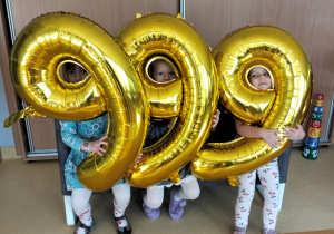 dzieci pozują do zdjęcia z balonami obrazującymi numer alarmowy 999
