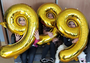 dzieci pozują do zdjęcia z balonami obrazującymi numer alarmowy 999