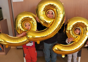 dzieci pozują do zdjęcia z balonami obrazującymi numer alarmowy 999