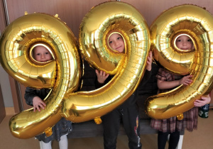 dzieci pozują do zdjęcia z balonami obrazującymi numer alarmowy 999