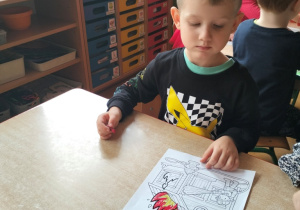 chłopiec koloruje obrazek przedstawiający pracę Strażaka