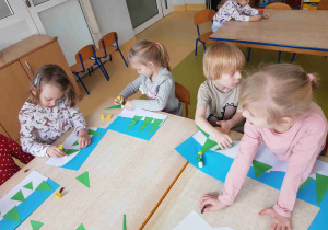 Dzieci przyklejają elementy zimowej pracy plastycznej