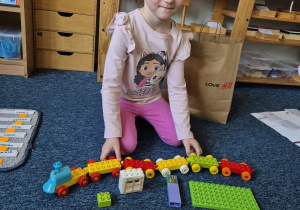 Dziewczynka pozuje do zdjęcia z klockami Lego