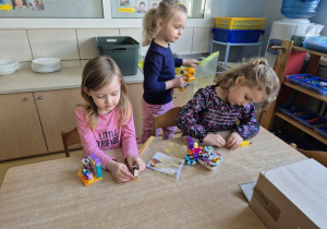 Dziewczynki budują z klocków Lego siedząc przy stoliku