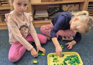 Dziewczynki budują budowlę z klocków Lego w jednym kolorze