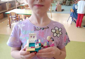 Ala trzyma w dłoniach zbudowaną przez siebie budowlę z klocków Lego