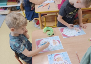 Chłopiec w trakcie przygotowywania kalendarza adwentowego - Mikołaja z numerami na brodzie