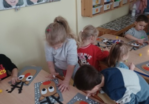 Dzieci stemplują palcami zanurzonymi w białej farbie śnieg wokół wyklejonego renifera