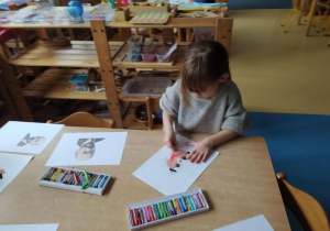 Dziewczynka siedzi przy stole i rysuje Janusza Korczaka