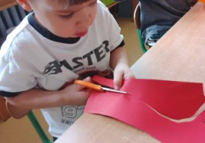 Miłosz wycina swoją dłoń odrysowaną na kolorowym papierze