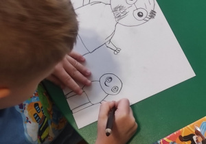 Chłopiec szkicuje portret Janusza Korczaka.