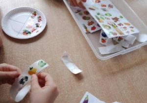 Dzieci przyklejają na papierowe talerzyki owoce i warzywa