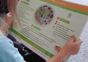 Dziewczynka ogląda planszę dotyczacą zdrowego żywienia