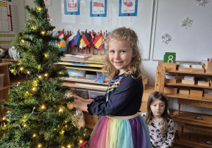 Dziewczynka zawiesza ozdobę na choince