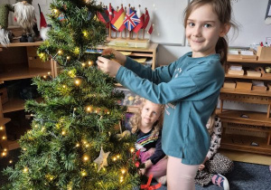 Dziewczynka zawiesza ozdobę na choince