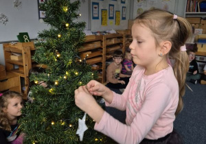 Dziewczynka zawiesza ozdobę na choince