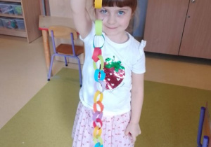 Maja pozuje do zdjęcia z wykonanym przez siebie łańcuchem z pasków kolorowego papieru