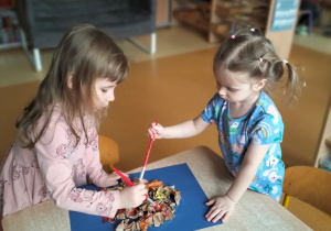 Zosia z Julą malują farbami słońce ze zgniecionego papieru
