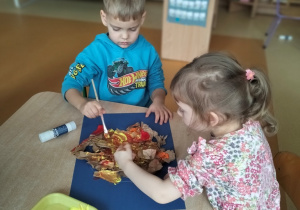 Zachary z Igą malują farbami słońce ze zgniecionego papieru