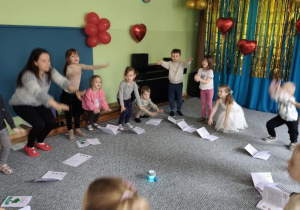 Dzieci oraz prowadząca zajęcia wykonują przysiady