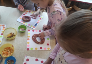 Dzieci dekorują pączki kolorową posypką.