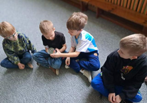 Dzieci siedzą na dywanie i oglądają puszkę mleka kokosowego