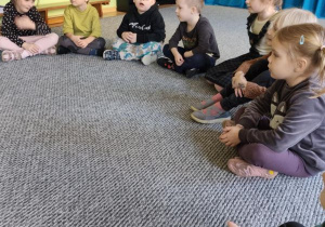 Dzieci siedzą w kręgu na dywanie