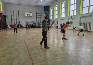 Dzieci biegają po sali i odbijają piłkę