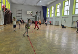 Dzieci biegają po sali i odbijają piłkę