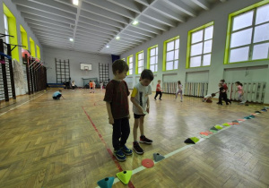 Chłopcy oglądają krążki i znaczniki ułożone na lini boiska