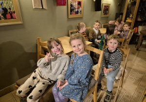 Dzieci siedzą na krzesełkach i czekają na rozpoczęcie przedstawienia