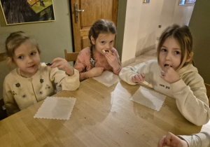 Dziewczynki siedzą przy stoliku i jedzą ciasteczka